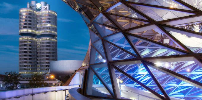 BMW Zentrum bei Nacht hinter dem beleuchteten Glasdach des Olympiaparks, München