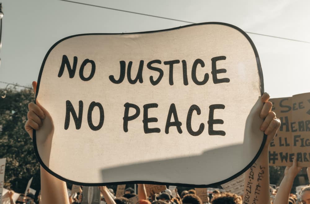 Keine Gerechtigkeit - kein Frieden - Demonstrantin hebt Protestschild hoch