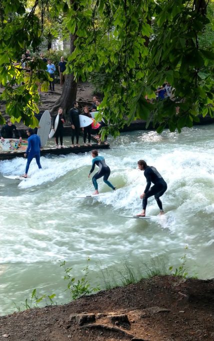 drei Surfer auf dem Eisbach im Englischen Garten