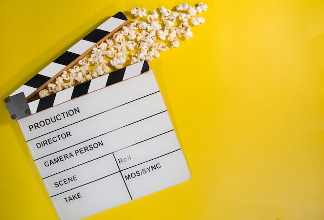 Filmklappe mit Popcorn vor weißem Hintergrund